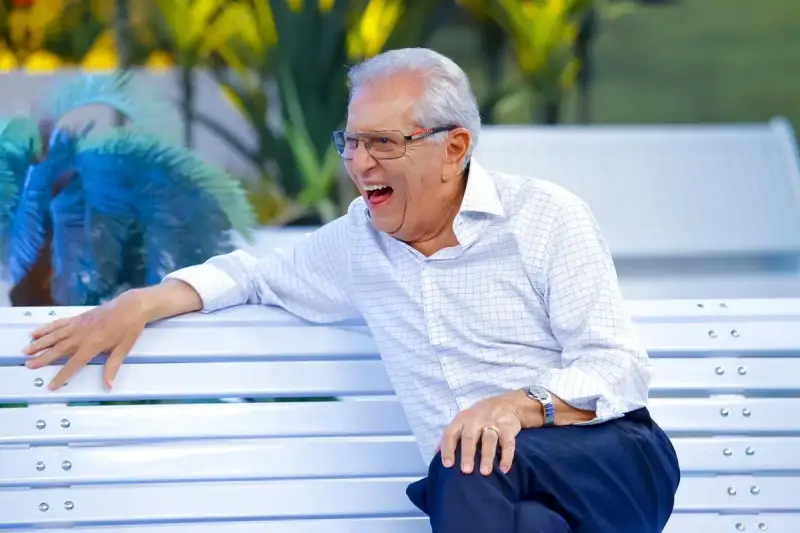 Carlos Alberto da Nóbrega sentado no Banco do programa A Praça é Nossa representando uma retrospectiva em que nada muda