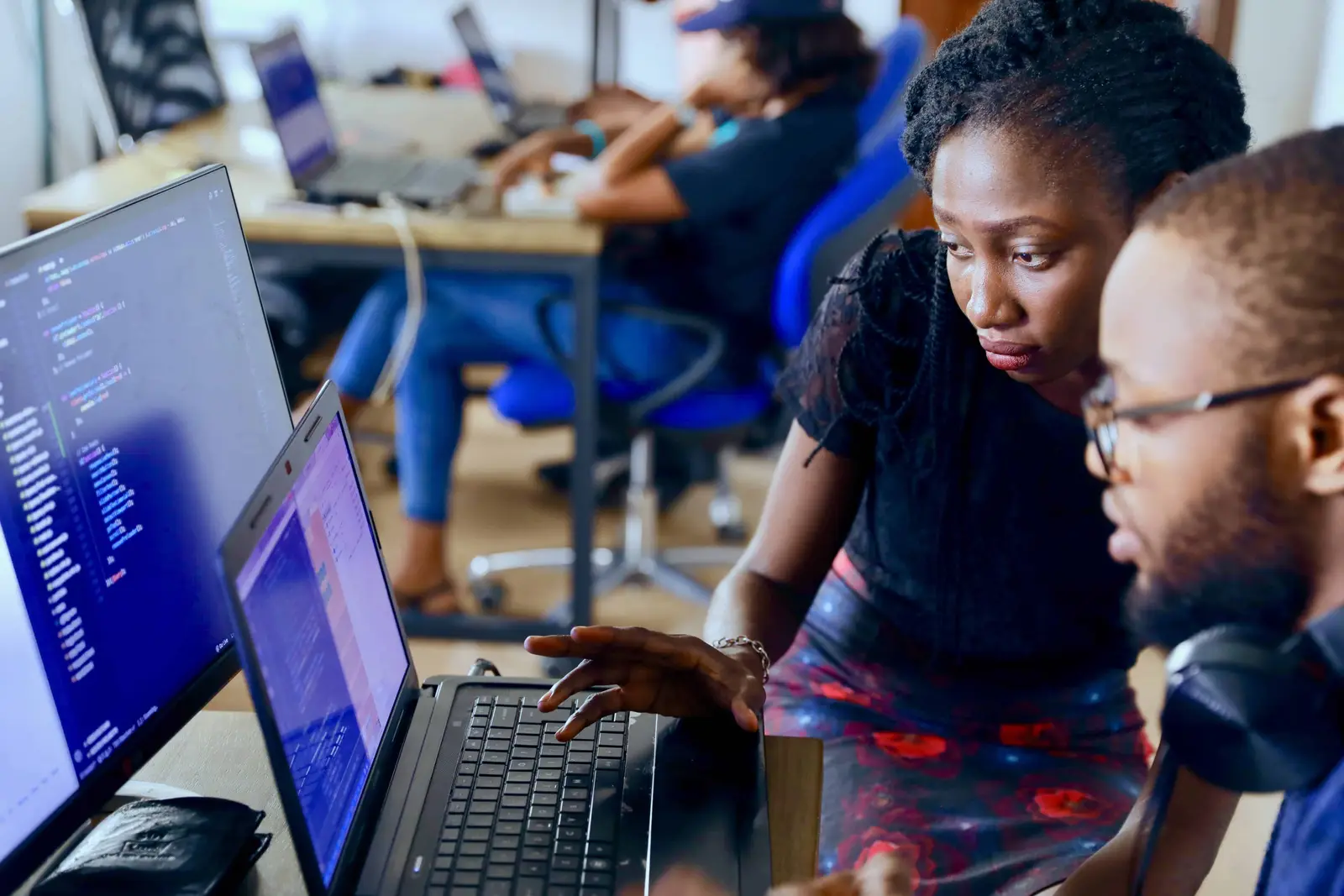 Duas pessoas olhando uma tela de computador com códigos